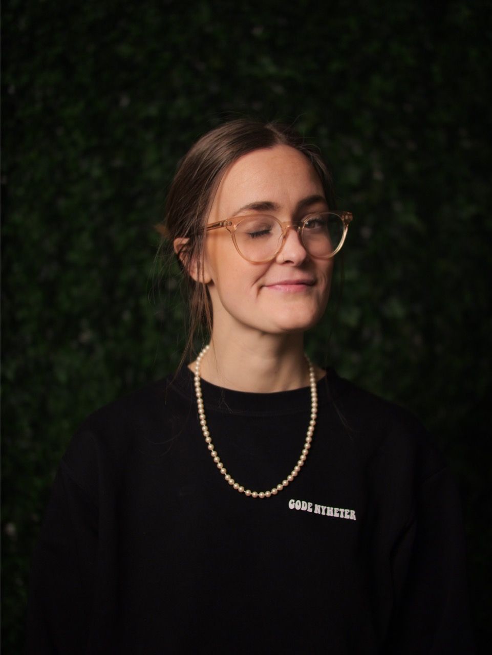 Alvilde smiler fornøyd med lukkede øyne, i genser med trykket «Gode nyheter».
